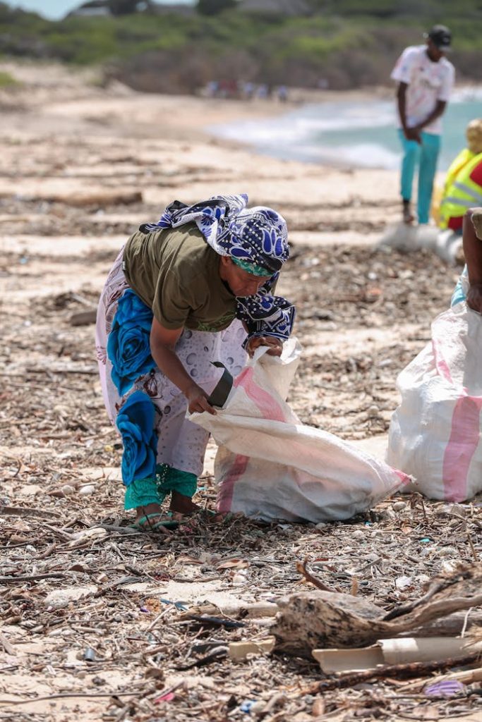 Woman collecting debris on a beach in Lamu County, Kenya. Environmental conservation effort.