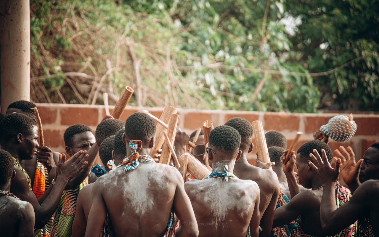 Group of men participating in a traditional ceremony in Abomey Calavi, showcasing tribal attire and rituals.