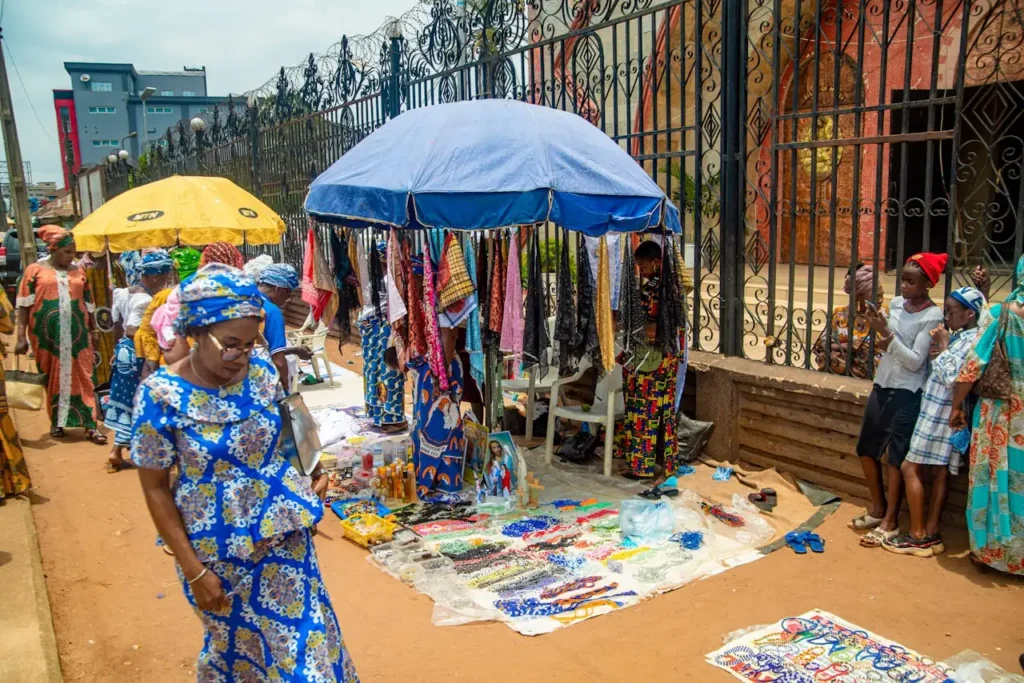 Mission Colorful outdoor market scene in Benin City, Nigeria, showcasing vibrant fabrics and local merchandise.