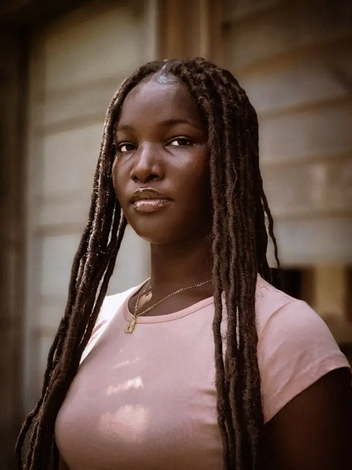 A striking portrait of a woman with long dreadlocks in front of a wooden wall, Benin City, Nigeria.