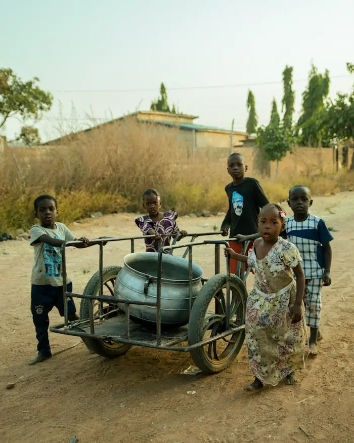 Charming scene of children in Benin playing with a metal cart on a sunny day.