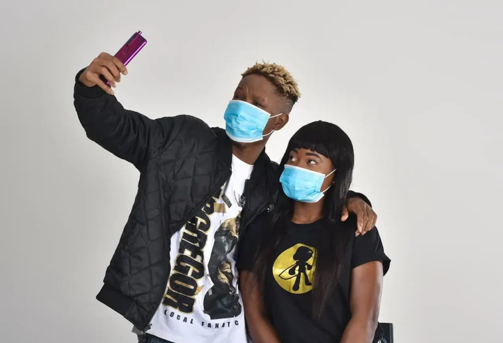 A young man and woman with face masks taking a selfie, capturing pandemic lifestyle essentials.