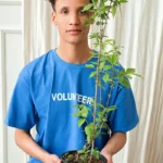 Young adult holding a potted plant, symbolizing volunteerism and environmental care.
