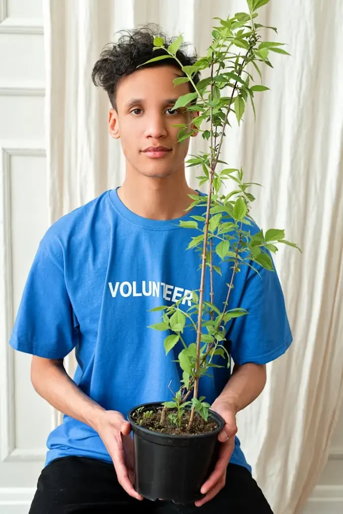 Mission Young adult holding a potted plant, symbolizing volunteerism and environmental care.